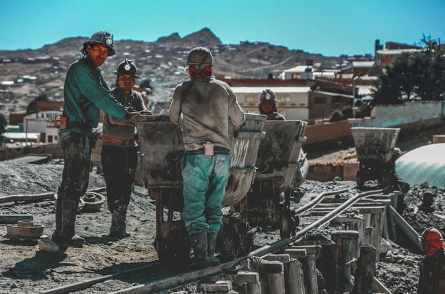 A group of miners talking around mining carts.