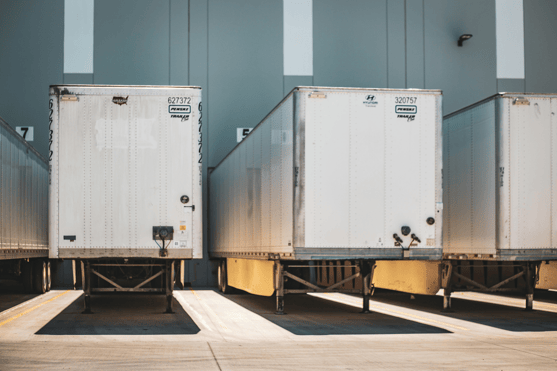 Semi-truck trailers are parked at a warehouse loading dock.
