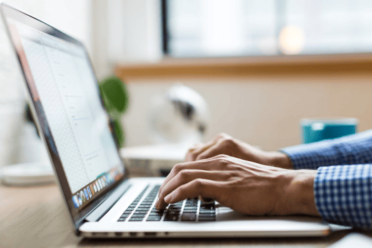 Person typing on a silver Macbook