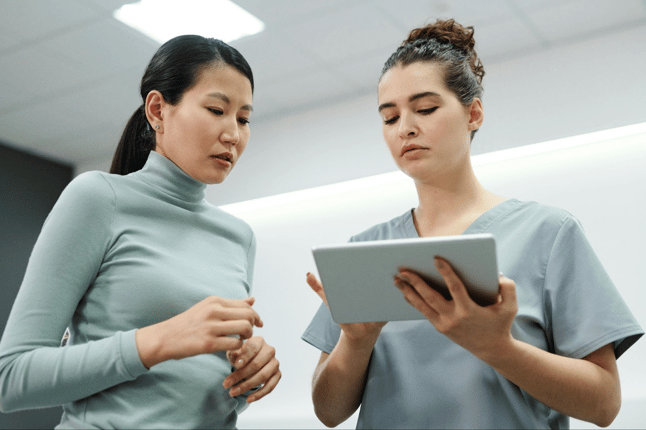 Nurse taking notes on tablet while talking with patient
