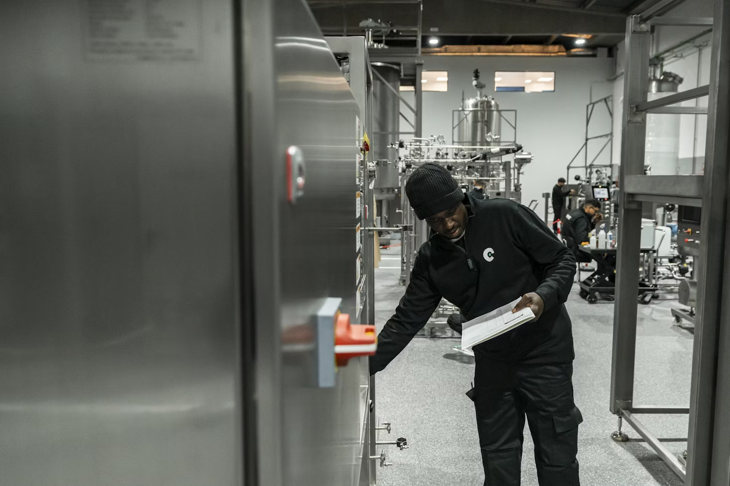 Technician inspecting industrial equipment in a manufacturing facility while holding a checklist.