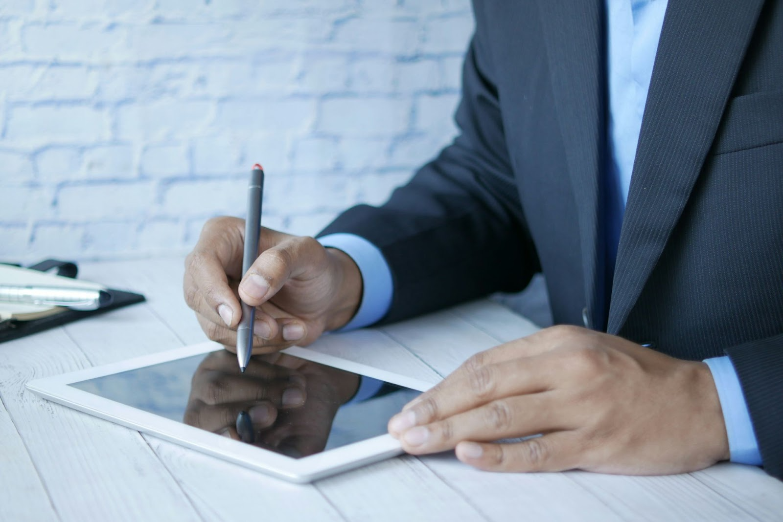 Professional in a business suit writing on a digital tablet, illustrating the documentation process for a non-conformance report.